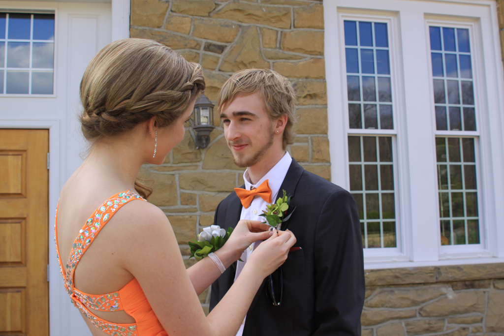 Stephanie putting on Marcus' Boutineer