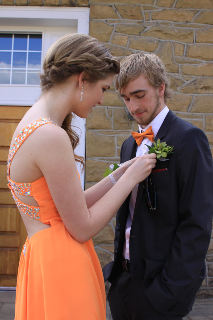 Stephanie putting on Marcus' Boutineer